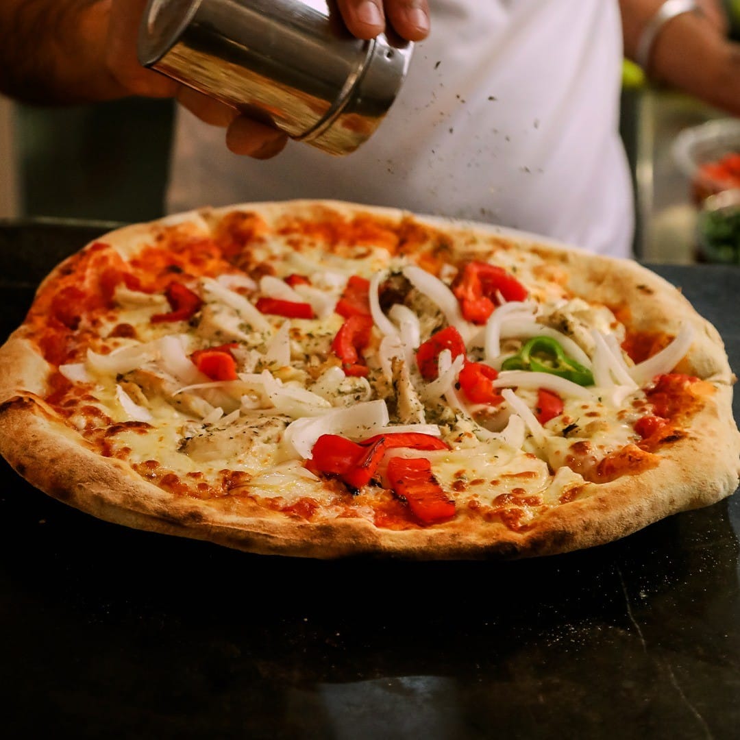 Pizza con pimiento rojo, verde, cebolla y orégano de una pizzería de málaga
